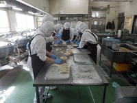 調理員さんが津ぎょうざのあんを皮に包んでいるところ①